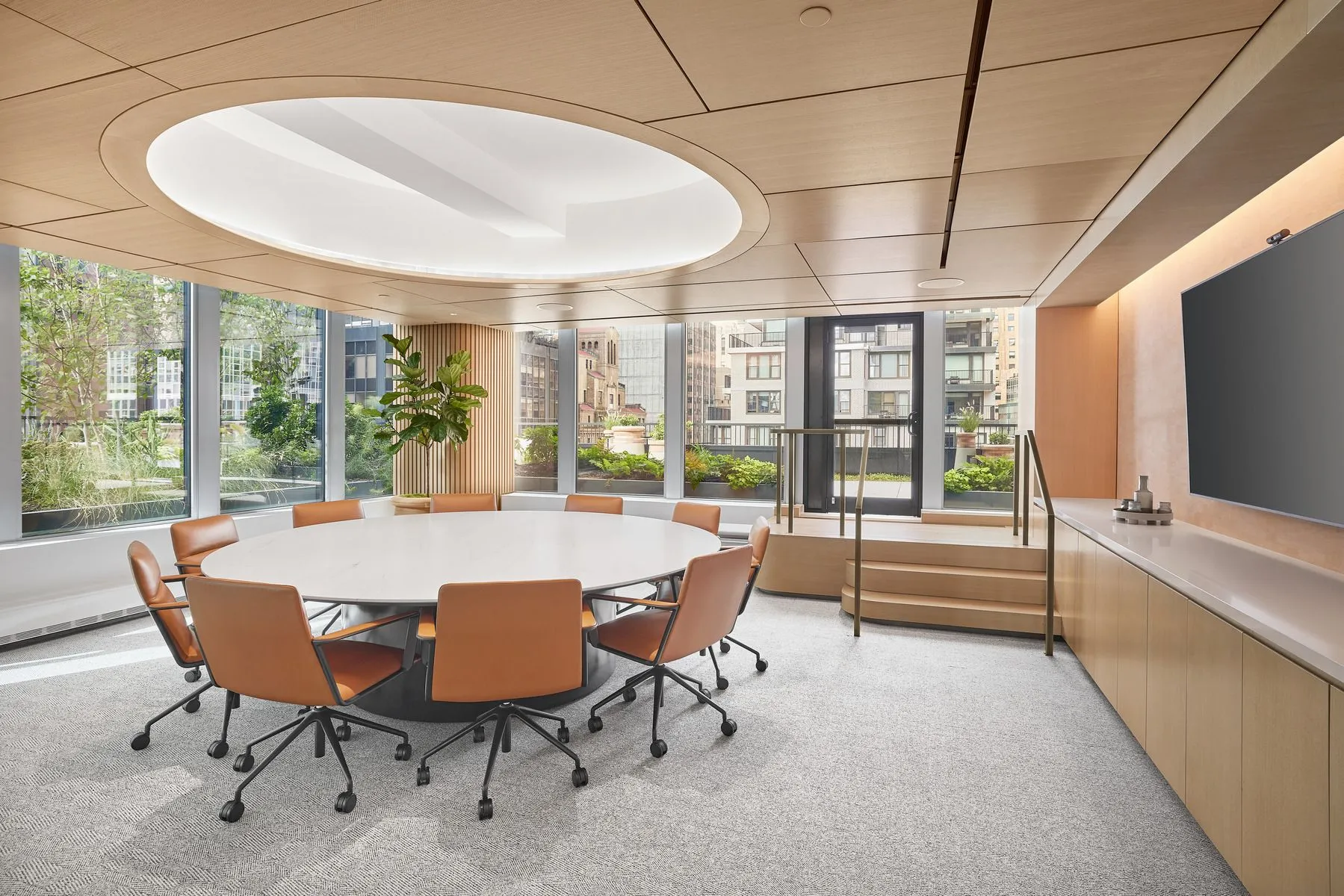 A spacious conference room with a round table surrounded by brown-leather chairs at 825 Third Avenue