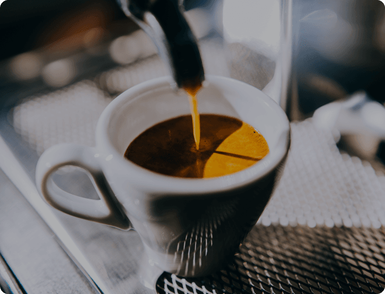 A coffee cup being filled with freshly brewed coffee.