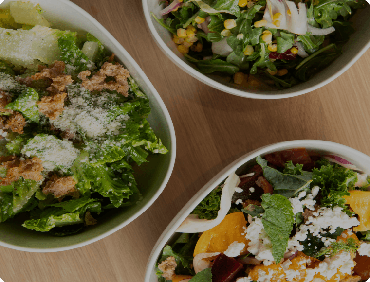 Three bowls of fresh Romaine salad topped with crispy bread crumbs, crumbled feta cheese, and a variety of herbs. Displayed in an appetizing and colorful presentation.