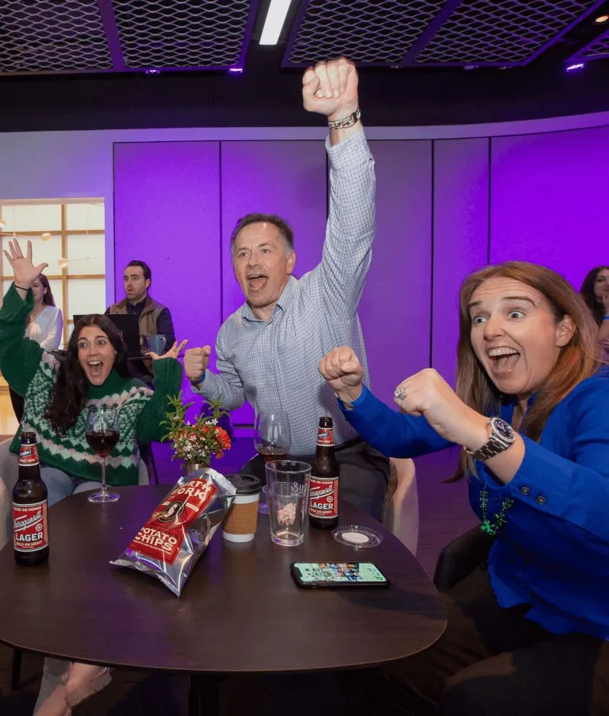 A group of people enjoying drinks at a table, with beer and a bottle of wine on display during a Well& by Durst event.