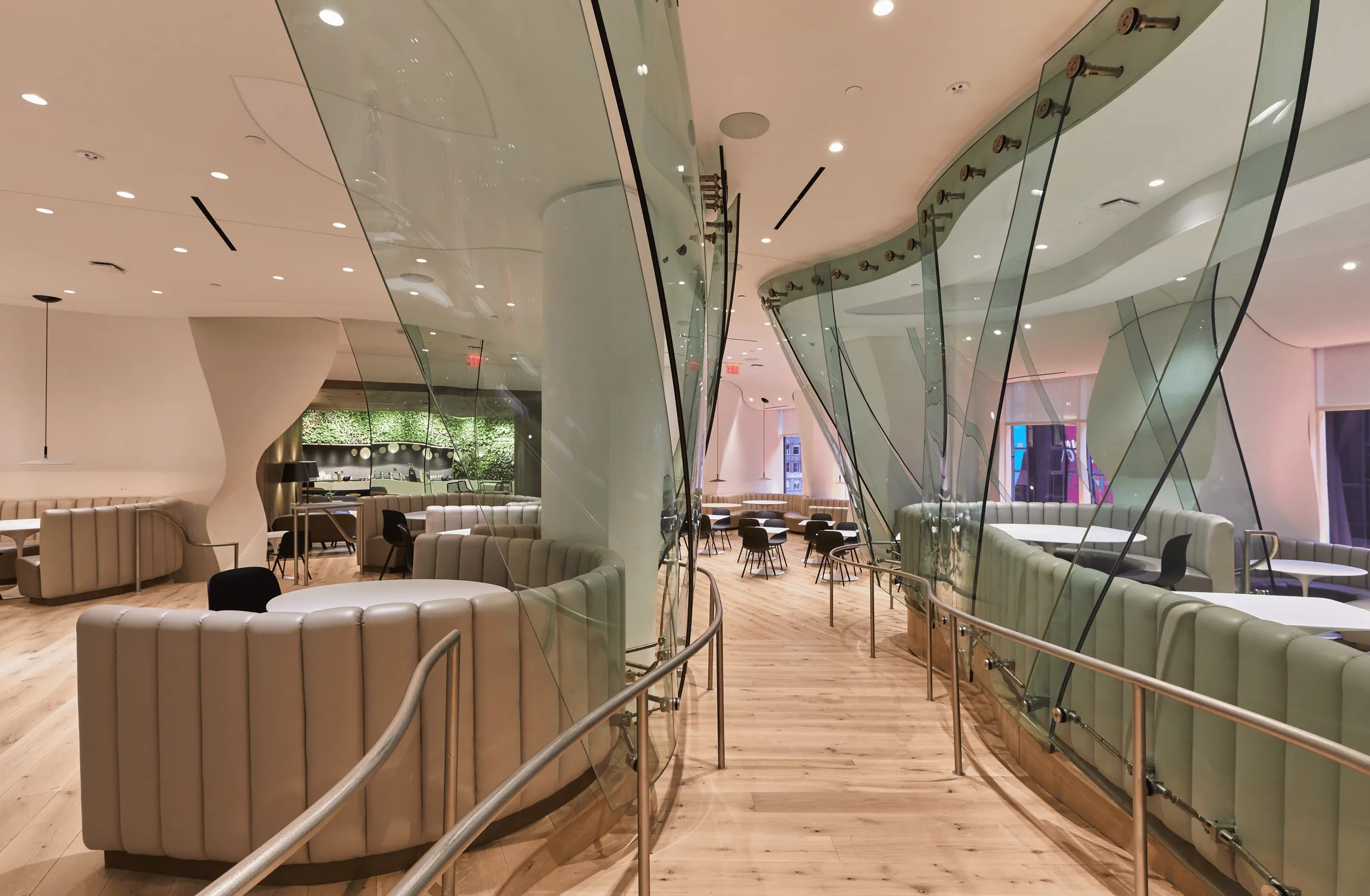 A contemporary restaurant with glass walls and a bar. With bright ilumination comming from natural light.