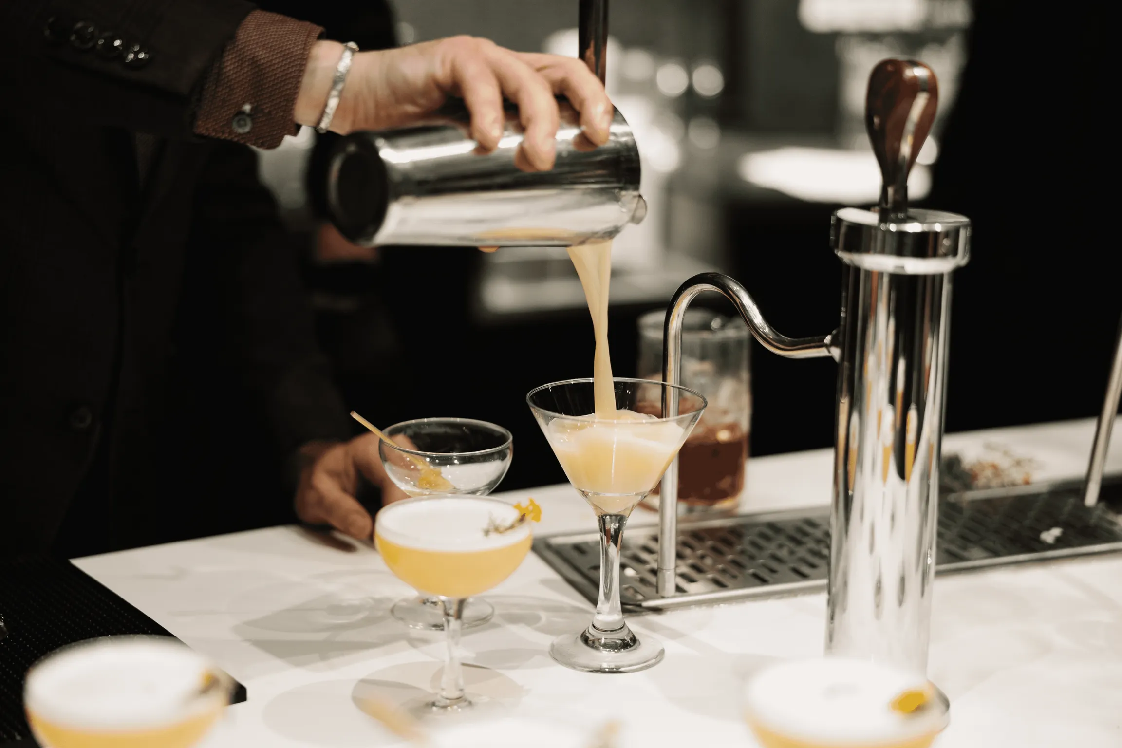 A bartender skillfully pours a cocktail into a glass, creating a visually appealing and refreshing drink.