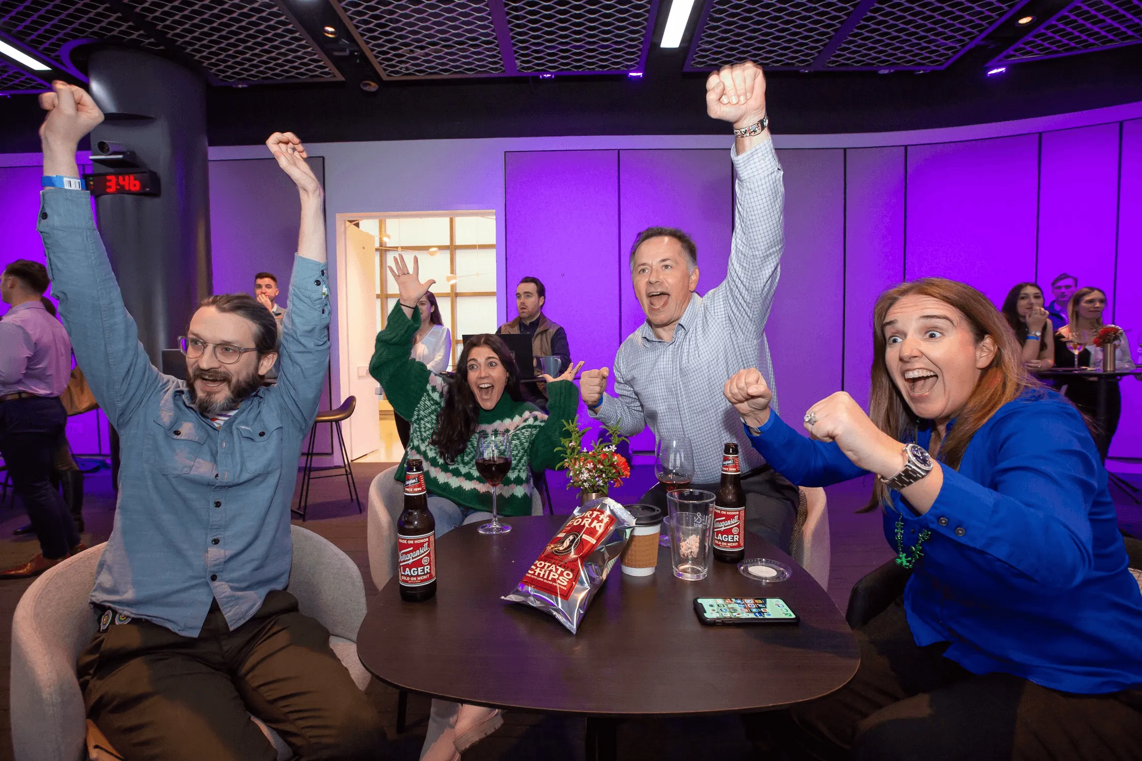 A group of people enjoying drinks at a table, with beer and a bottle of wine on display during a Well& by Durst event.