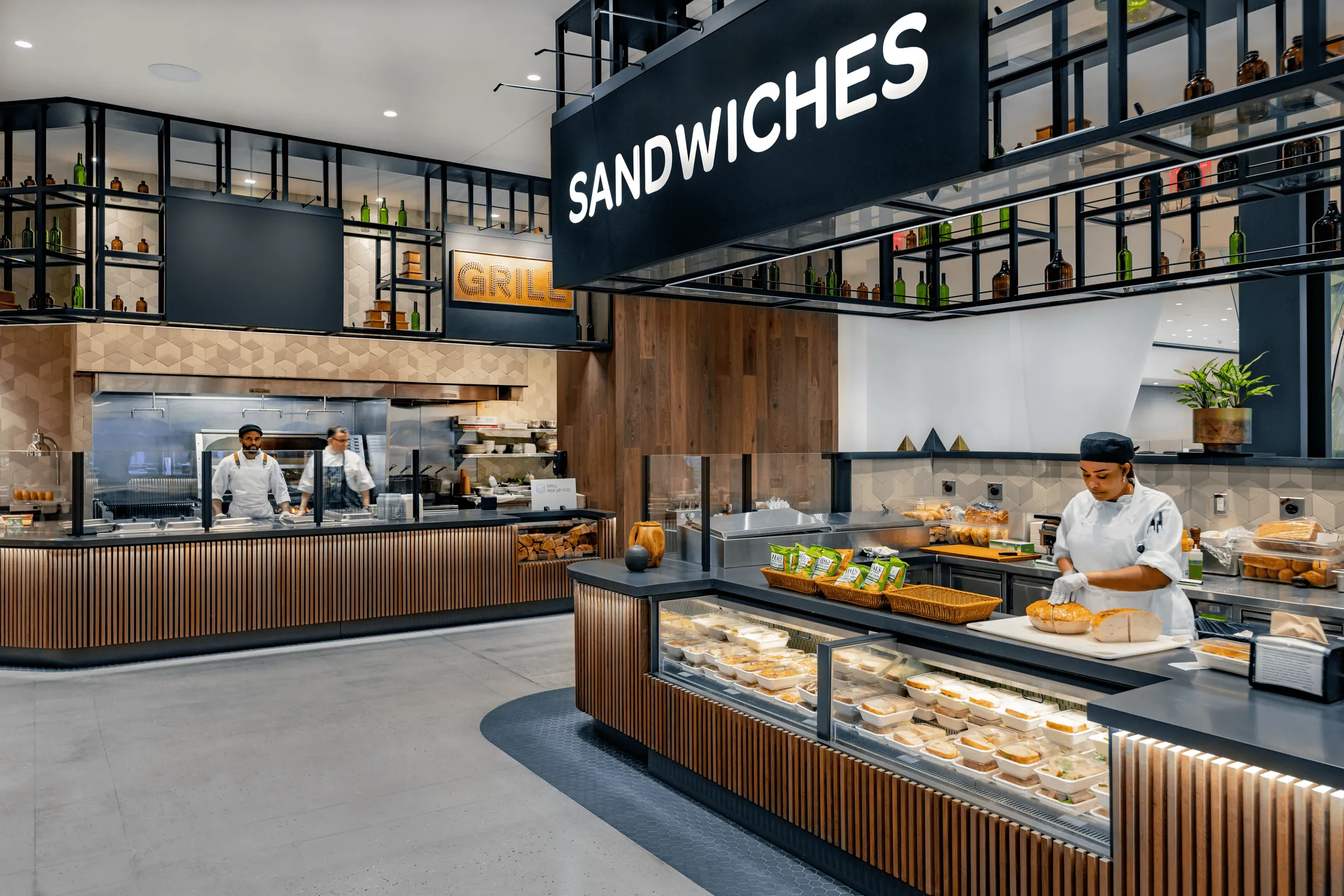 Modern Sandwich bar, with a juice station, seating area under soft lighting, and staff serving customers.
