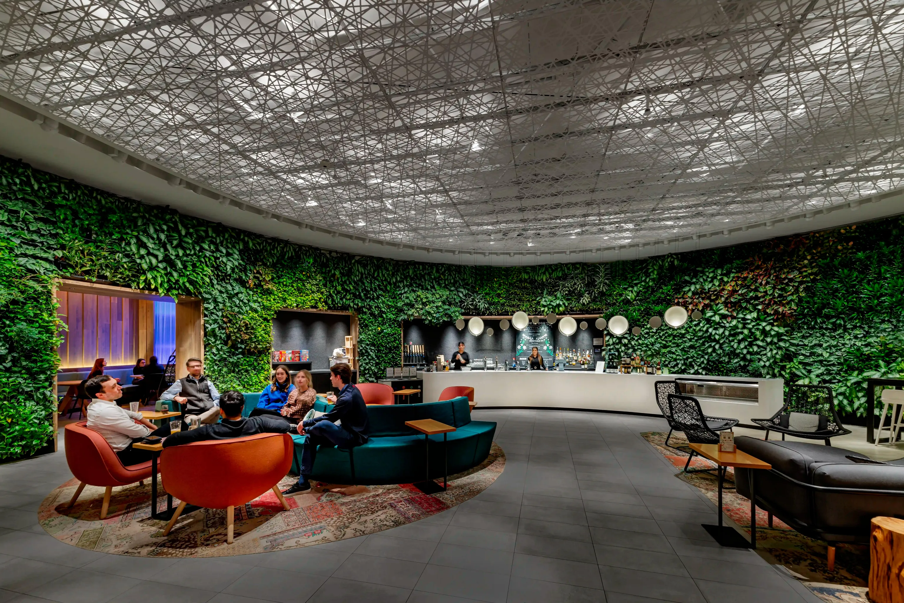 A lounge/cafe area showcasing lush green plants adorning the walls, creating a refreshing and vibrant atmosphere.