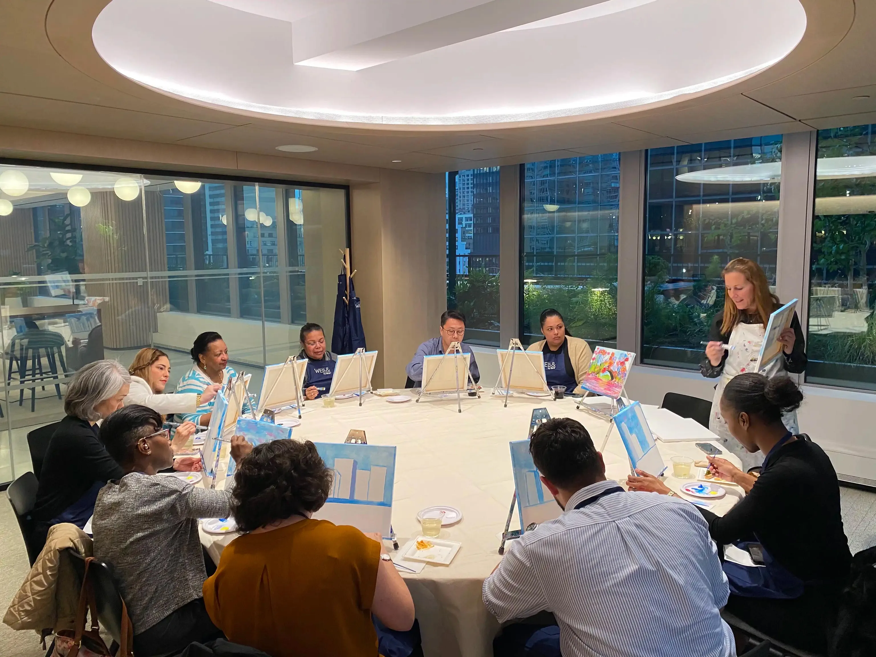 Individuals seated at a table with plants, taking part in a class focused on creating mini terrariums