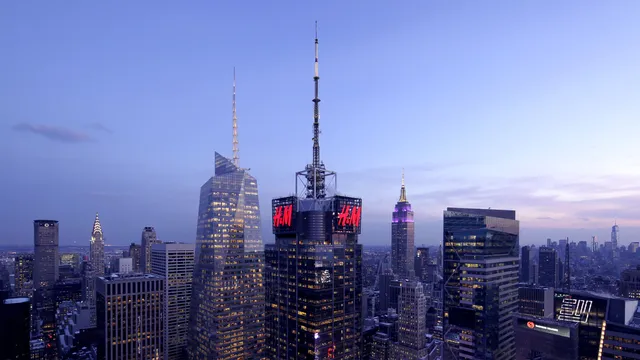 151 West 42nd Street. A sleek office tower with a glass facade featuring an H&M logo right below the spire.