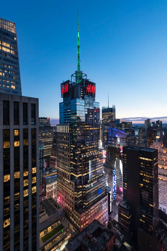 151 West 42nd Street. A sleek office tower with a glass facade featuring an H&M logo right below the spire.