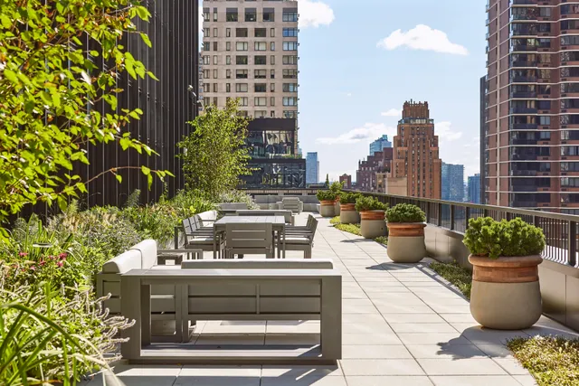 A serene rooftop terrace adorned with benches and lush green plants, offering a peaceful retreat. Located at 825 Third Ave's 12th floor.